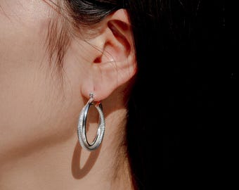 Dikke zilveren oorringen: statementsieraden met textuur