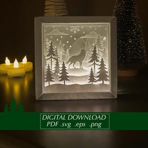 Puede incluir: Una pieza de arte cuadrada e iluminada que representa un lobo en una escena de bosque invernal. El diseño está recortado en papel blanco, con una silueta de un lobo, árboles y copos de nieve. El marco es de color gris neutro. El texto en la parte inferior dice "DESCARGA DIGITAL PDF .svg .eps .png".