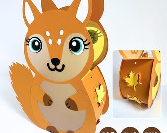 Könnte beinhalten: Eine Eichhörnchen-Figur aus Papier mit großen Augen, langen Wimpern und einem hellbraunen Bauch. Das Seitenteil zeigt ausgeschnittene gelbe Ahornblattformen. Der Text PDF, SVG und PNG erscheint in braunen Kreisen am unteren Bildrand.
