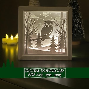 Könnte beinhalten: Eine weiße, beleuchtete Schattenbox mit einer Winterszene, die eine Eule auf einem Ast zeigt. Das Design umfasst Bäume, Schneeflocken und den Text "DIGITAL DOWNLOAD PDF .svg .eps .png".