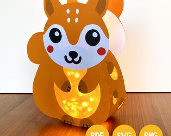 Könnte beinhalten: Eine Papier-Eichhörnchen-Laterne mit leuchtend orangefarbenem Körper, weißen Gesichtsmarkierungen und großen schwarzen Augen. Das Eichhörnchen hat ein gelbes Licht im Bauch und Eichel-Muster an der Seite. Drei gelbe Kreise zeigen den Text PDF, SVG, PNG.
