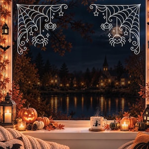 Puede incluir: Adhesivos de ventana de telaraña blanca con arañas colgantes y estrellas en las esquinas superiores. El diseño incluye dos patrones de telaraña simétricos con arañas colgantes, cada una con una cara sonriente, sobre un cristal transparente.