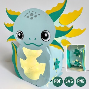 Könnte beinhalten: Eine hellblaue Axolotl-Laterne aus Papier mit gelben und türkisfarbenen Kiemen, großen schwarzen Augen und einem leuchtenden Inneren. Die Seitenwand zeigt türkisfarbene Blumenausschnitte. Das Bild enthält Text für PDF, SVG und PNG.