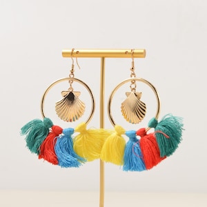May include: A pair of gold hoop earrings with a seashell charm and colorful tassels. The tassels are red, blue, yellow, and green.