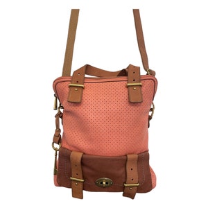 Puede incluir: Un bolso de hombro de cuero rosa y marrón con un diseño perforado y múltiples correas y hebillas.