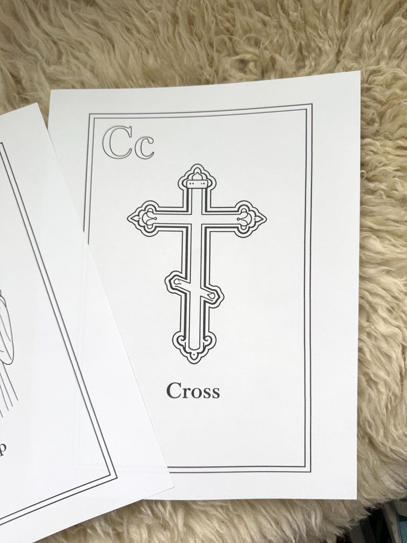 May include: A black and white illustration of a cross on a white card. The card has the letter "Cc" in the upper left corner and the word "Cross" at the bottom. The card is on a textured, light-colored surface.