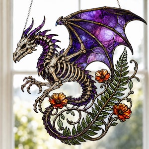 May include: A stained glass suncatcher featuring a skeletal dragon with purple wings, surrounded by green fern leaves and orange flowers. The dragon has a cream-colored bone structure and is suspended by a thin metal chain for window display.