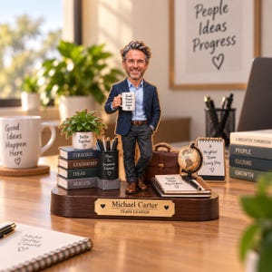 Puede incluir: Una figura de escritorio personalizada de un hombre con blazer azul y pantalón oscuro sosteniendo una taza que dice Good People Great Work. La base incluye una placa con el nombre Michael Carter Team Leader, libros en miniatura y un globo.