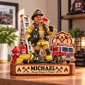 Puede incluir: Un expositor de madera personalizado con una figura de bombero en equipo color canela, casco, hacha, escalera, hidrante, manguera y camión de bomberos. La base está grabada con el nombre MICHAEL y el texto Always Ready To Protect.