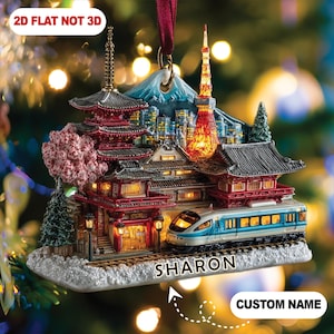 May include: Ornament featuring a Japanese scene with a pagoda, Tokyo Tower, and a train. The ornament is detailed with red, white, and blue accents, and the text "2D FLAT NOT 3D" is visible. The name "SHARON" is also displayed.