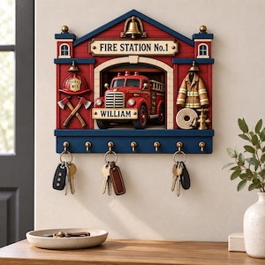Może przedstawiać: Drewniany wieszak na klucze w kształcie remizy strażackiej z czerwonym wozem strażackim pośrodku. Tabliczka zawiera napis FIRE STATION No.1 oraz WILLIAM. Zawiera złoty dzwonek, hełm, dwa toporki, kurtkę i wąż. Sześć mosiężnych haczyków utrzymuje trzy zestawy kluczy.