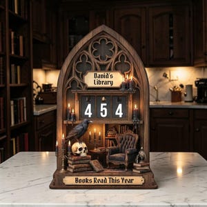 Könnte beinhalten: Ein Bücherregal im gotischen Stil aus Holz mit dem Text "David's Library" und "Books Read This Year". Es zeigt einen Raben, einen Schädel, Bücher, Kerzen und einen kleinen Stuhl. Die Zahl "454" wird auf einem digitalen Zähler angezeigt.