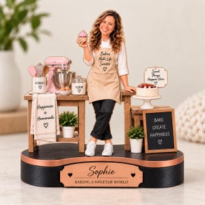 May include: A custom figurine display featuring a person in a tan apron with the text Bakers Make Life Sweeter, a pink stand mixer, a utensil holder, a flour jar, a cake on a stand, and signs reading Happiness is Homemade and BAKE CREATE HAPPINESS.