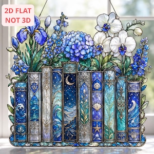 May include: A 2D flat stained glass suncatcher featuring a row of nine decorative book spines in shades of blue, teal, and white, topped with a vibrant arrangement of blue irises, hydrangeas, and white orchids. The text 2D FLAT NOT 3D is visible.