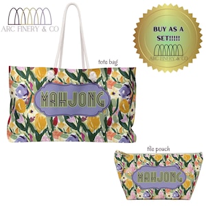 Puede incluir: Un conjunto de dos bolsas con estampado floral con la palabra "MAHJONG" en una pancarta morada y verde. La bolsa más grande es una bolsa de mano con asas de cuerda blanca. La bolsa más pequeña es una bolsa para fichas. Ambas bolsas tienen un fondo blanco con un estampado floral en tonos amarillos, rosas, morados y verdes.