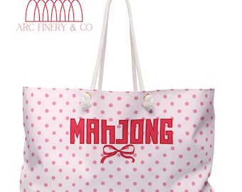 May include: A pink and white polka dot tote bag with the word "Mahjong" in red letters and a red bow. The bag has white rope handles.