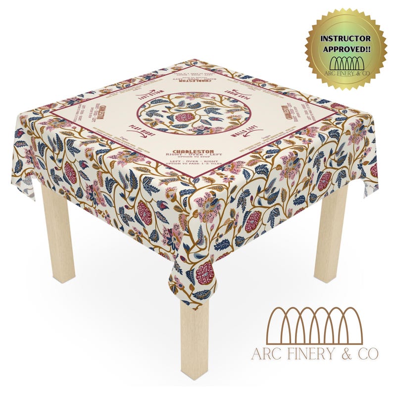 May include: A white tablecloth with a floral pattern and a circular design in the center. The design features a tree with leaves and flowers, and the text "Charleston Right Over Left" is written around the circle. The tablecloth is on a wooden table with four legs.