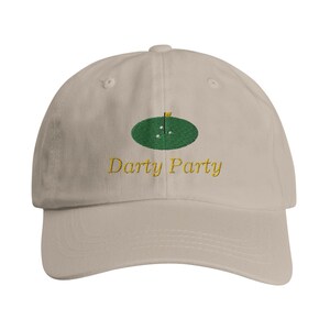 May include: A beige baseball cap with an embroidered green golf course and the text "Darty Party" in yellow.