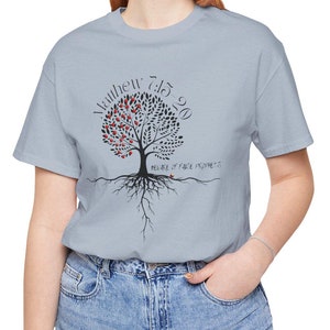 Puede incluir: Una camiseta azul claro con un gráfico de árbol negro y rojo. El árbol tiene las palabras "Mateo 7:15-20" escritas a su alrededor. Las raíces del árbol tienen las palabras "Fruto de los falsos profetas" escritas en ellas.