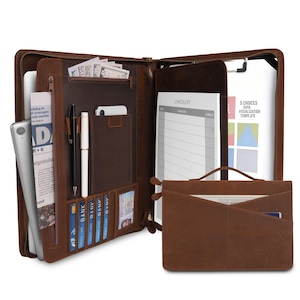 May include: Open brown leather portfolio with multiple compartments, including slots for pens, cards, and a phone. The portfolio is open, revealing a checklist and a data visualization template. A smaller brown leather document holder is also visible.