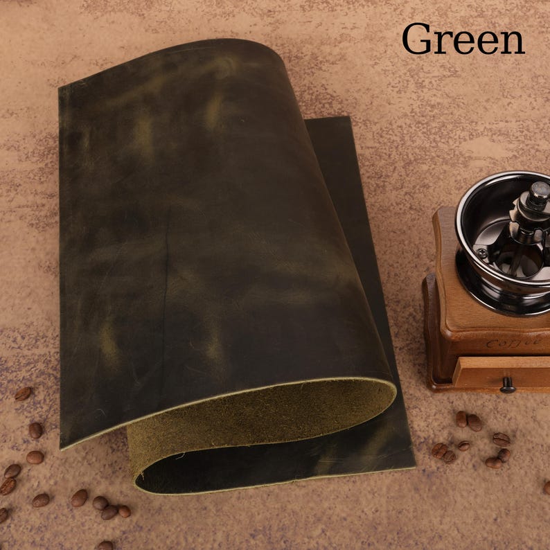 May include: A sheet of green leather with a distressed finish. The leather has a dark green color with lighter green highlights. The word "Green" is printed in black in the upper right corner.