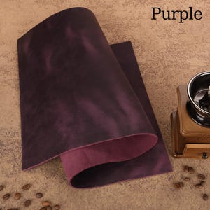 May include: A sheet of purple leather with a textured surface, folded over to reveal a lighter purple underside. The word "Purple" is in the upper right corner. Coffee beans and a wooden coffee grinder are in the background.