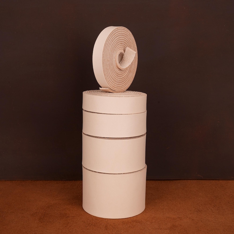 May include: A stack of five white leather straps, rolled up and ready to be used for crafting projects.