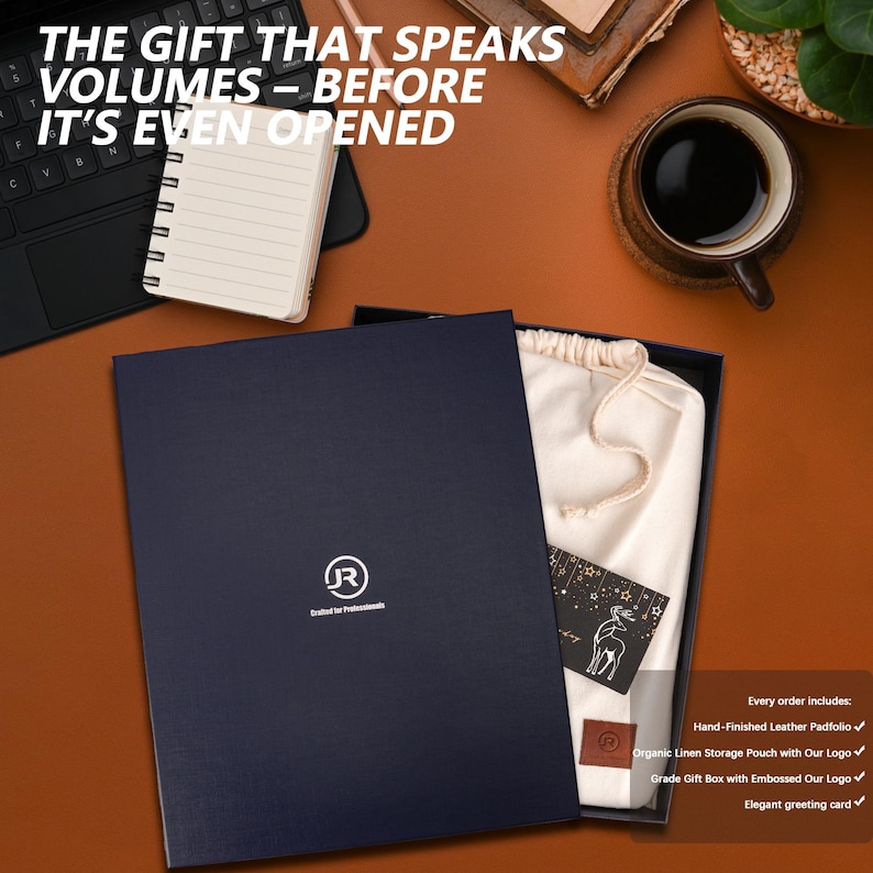 May include: A navy blue gift box with a white logo that says "(JR) Crafted for Professionals". The box is open and shows a white cloth bag with a drawstring, a small card with a deer illustration, and a brown leather padfolio.