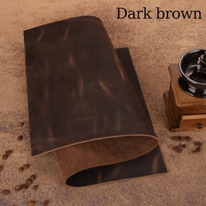 May include: Dark brown leather sheets with a distressed finish. The text "Dark brown" is visible in the upper right corner. A wooden coffee grinder and coffee beans are in the background. The leather has a rich, textured appearance.