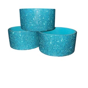 Puede incluir: Tres posavasos turquesas. Cada posavasos es cil&iacute;ndrico con un exterior brillante, similar a pedrer&iacute;a y un interior turquesa liso. Los posavasos est&aacute;n apilados en forma triangular sobre un fondo blanco.