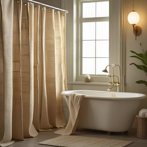 Puede incluir: Un cuarto de ba&ntilde;o con una ba&ntilde;era ovalada blanca y grifos de lat&oacute;n. Cortinas de ducha beige tejidas en el fondo. Una toalla beige est&aacute; sobre la ba&ntilde;era y una alfombra tejida est&aacute; en el suelo. Tambi&eacute;n se ven una ventana y una l&aacute;mpara de pared.