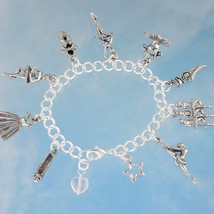 May include: A silver charm bracelet with a variety of ballet-themed charms, including a ballerina, a pair of ballet shoes, and a star. The bracelet is on a blue background.