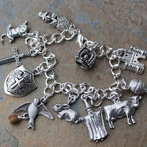 以下が含まれることがあります： 王冠、城、剣、盾、鳥、ウサギ、牛、杯、花など、さまざまなチャームが付いたシルバー製のチャームブレスレット。ブレスレットはシルバー製のチェーンリンクで作られています。