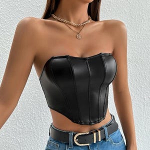 Peut inclure: Un haut de corset noir sans bretelles en similicuir avec un d&eacute;collet&eacute; en c&oelig;ur et un ourlet pointu. Le haut a un corsage ajust&eacute; et est accentu&eacute; par des coutures verticales.