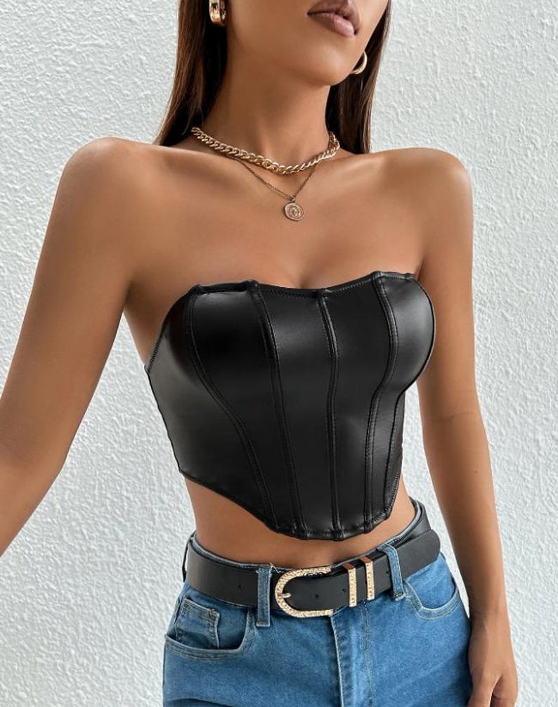 Peut inclure: Un haut de corset noir sans bretelles en similicuir avec un d&eacute;collet&eacute; en c&oelig;ur et un ourlet pointu. Le haut a un corsage ajust&eacute; et est accentu&eacute; par des coutures verticales.