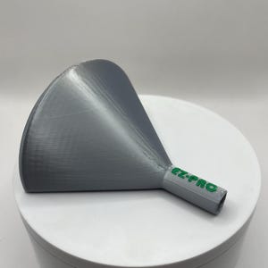 May include: A gray plastic funnel with a wide, curved opening and a narrow spout. The text "EZ-PRO" is printed in green on the spout. The funnel is designed for pouring liquids or powders.
