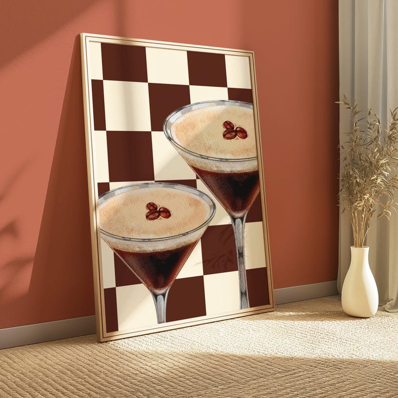 May include: A framed print of two coffee cocktails with a brown and white checkered background. The cocktails are in martini glasses and have a brown coffee base with a white foamy top. Coffee beans are visible on top of the foam.