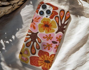 Puede incluir: Una funda de teléfono con un estampado floral en tonos naranja, rosa, amarillo y marrón. La funda tiene un fondo color crema y un acabado brillante. El diseño presenta flores estilizadas y formas orgánicas, creando una estética retro.