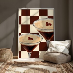 May include: Two espresso martinis with a brown and white checkered background. The drinks are garnished with coffee beans.