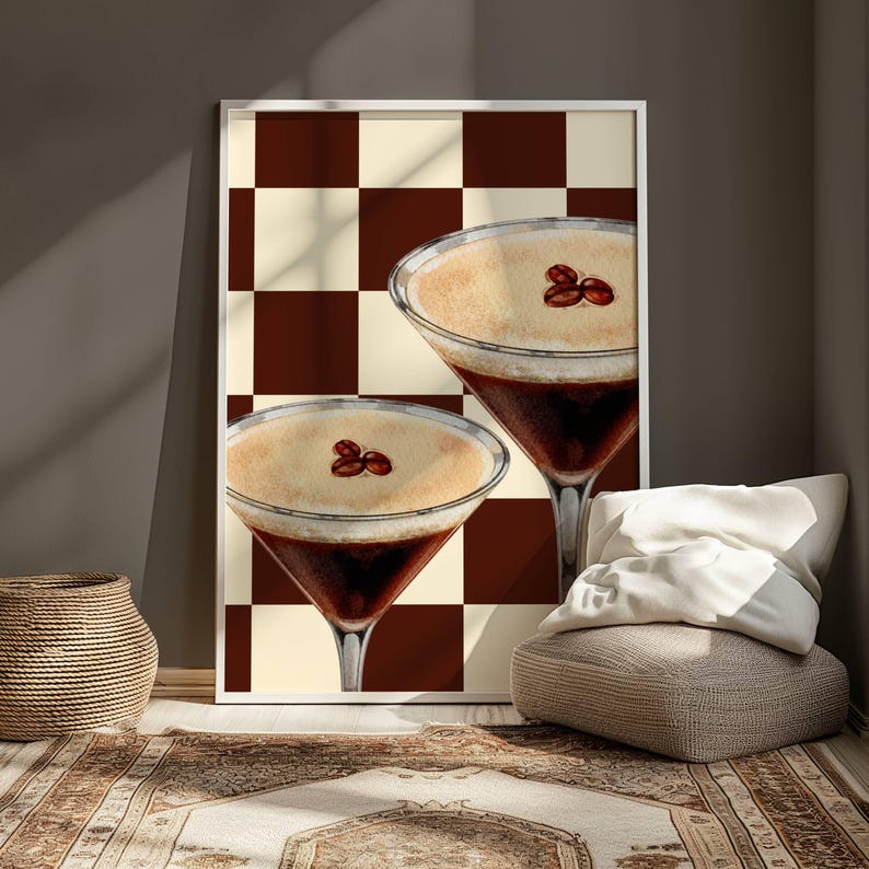 May include: Two espresso martinis with a brown and white checkered background. The drinks are garnished with coffee beans.