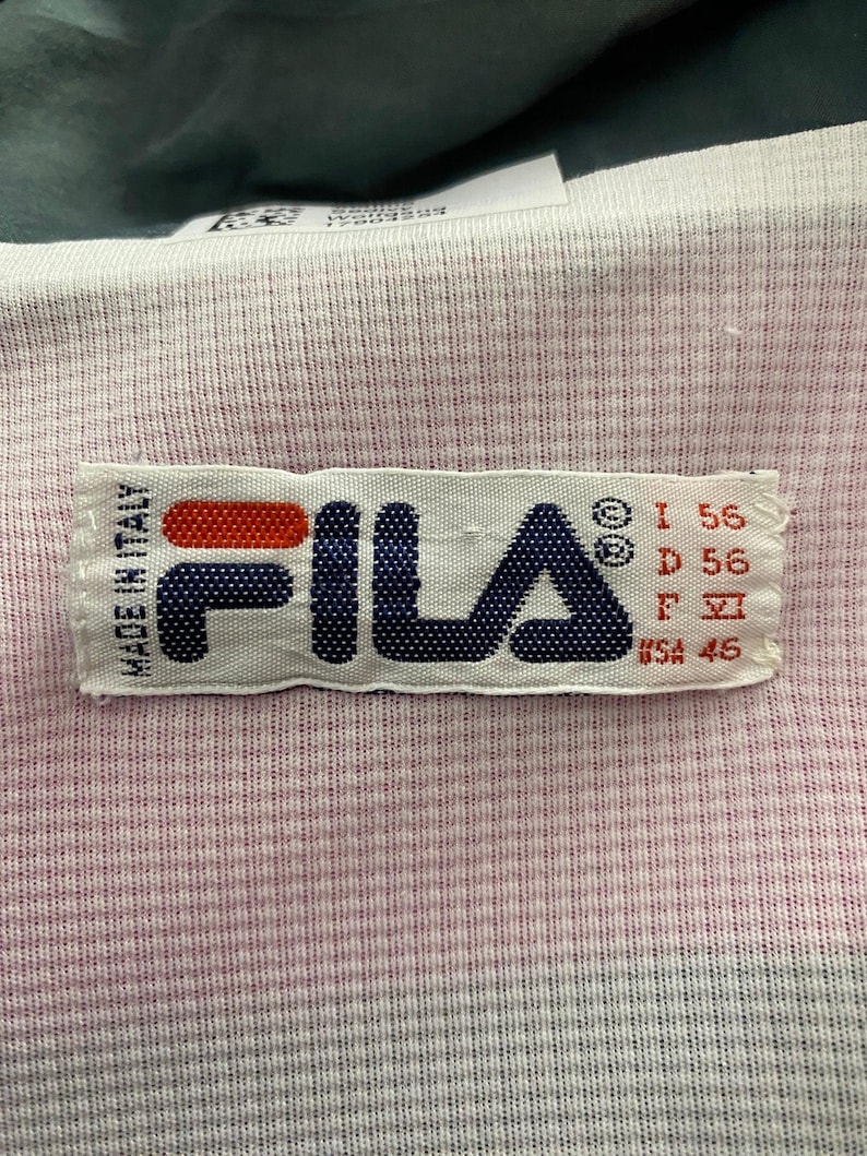 May include: White Fila label with red, blue, and black text. The label says "Fila" and "Made in Italy". It also has size information: "I 56", "D 56", "F 46", and "USA 46".