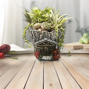 Könnte beinhalten: Ein grauer, steinartiger Pflanzer in Form eines kleinen Hauses mit einer braunen Tür und roten Blumen. Der Pflanzer ist mit grünen Sukkulenten gefüllt.