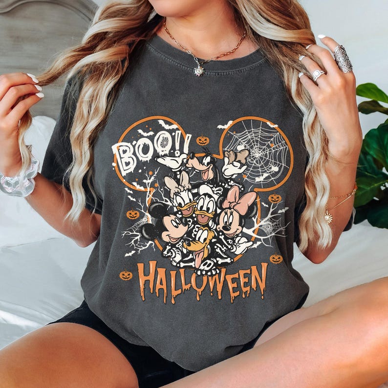 May include: A black t-shirt with a graphic of Mickey Mouse and friends dressed in Halloween costumes. The graphic includes the text "BOO!" and "HALLOWEEN".