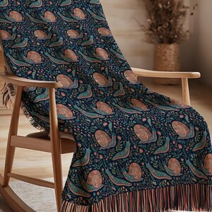 Navy throw blanket with a repeating pattern of snails and floral elements.