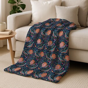 Navy blue throw blanket with a repeating pattern of colorful snails and flowers.