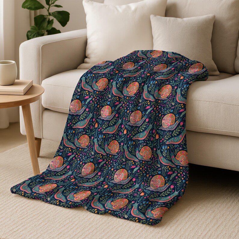 Navy blue throw blanket with a repeating pattern of colorful snails and flowers.