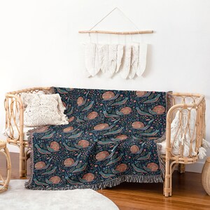 Woven blanket with a pattern of snails, flowers, and leaves in shades of blue and pink.