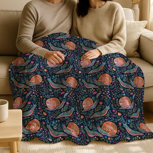 Couple under dark blue blanket with colorful snail and floral pattern.