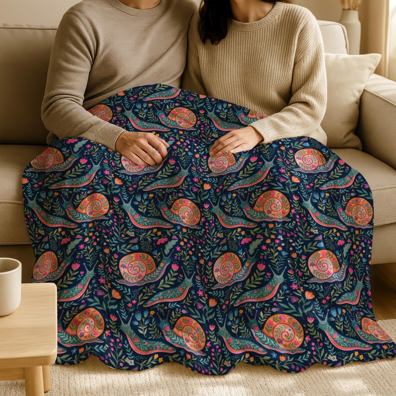 Couple under dark blue blanket with colorful snail and floral pattern.