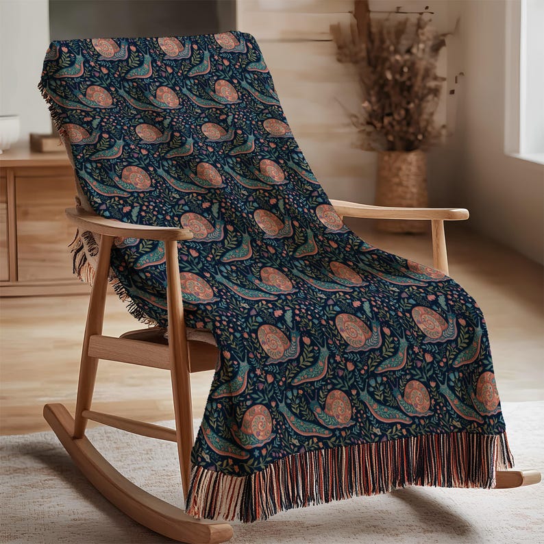 Navy throw blanket with a repeating pattern of snails and floral elements.